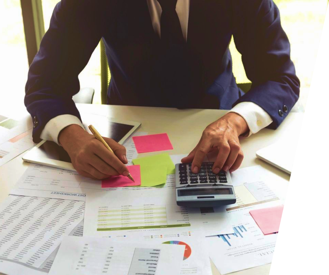 Businessman reviewing financial data and using calculator.